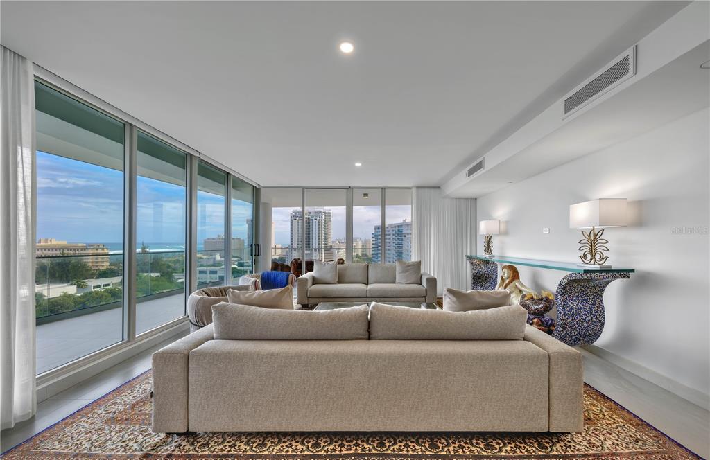 A modern living room features two beige sofas, a patterned rug, and floor-to-ceiling windows — 540 AVE. DE LA CONSTITUCION UNIT 1101, SAN JUAN, PR