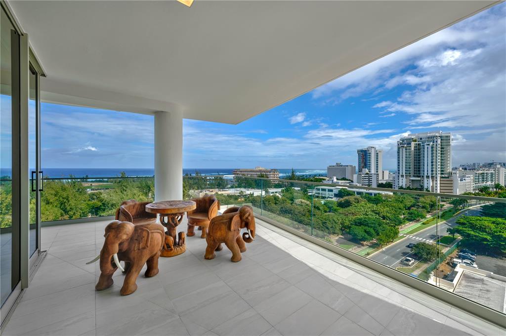 A balcony with elephant-shaped wooden furniture overlooks a city, park, and the ocean — 540 AVE. DE LA CONSTITUCION UNIT 1101, SAN JUAN, PR