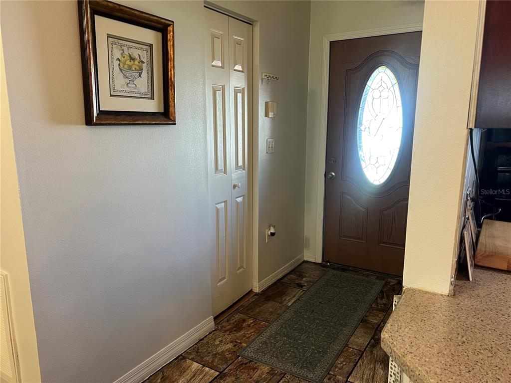 An entryway features a brown front door, a white bi-fold closet, and tiled flooring — 910 LOUVRE COURT, KISSIMMEE, FL