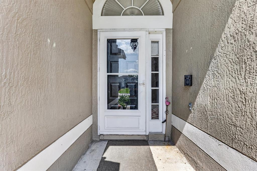 A white storm door with a sidelight is set within a stucco entryway — 2902 AFTON CIRCLE, ORLANDO, FL