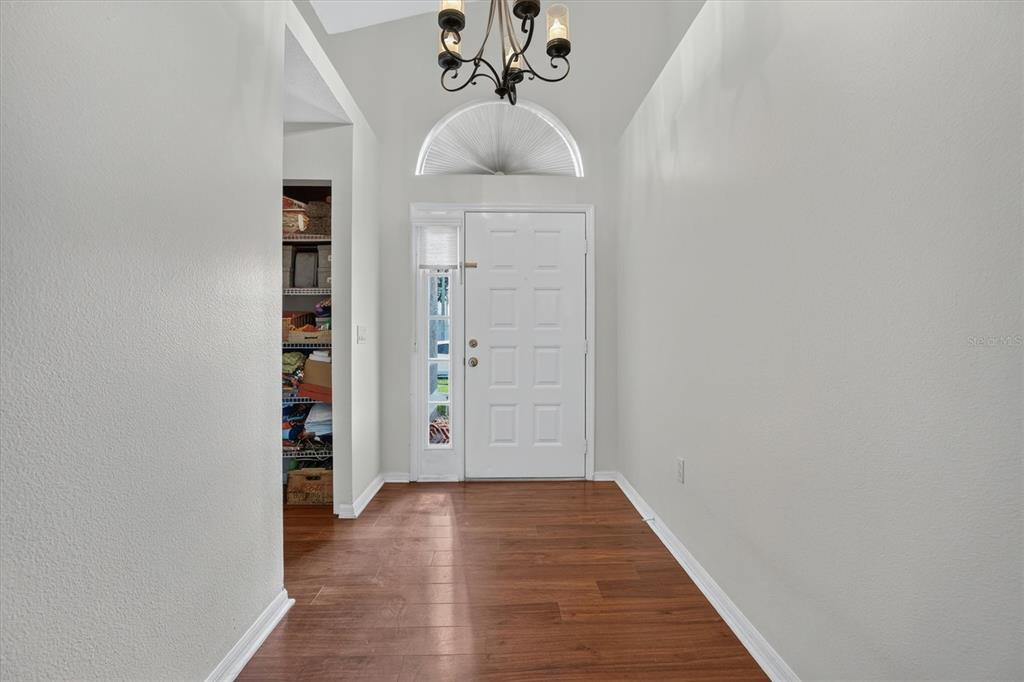 A bright entryway features wood-look flooring, a white front door, and a decorative chandelier — 2902 AFTON CIRCLE, ORLANDO, FL