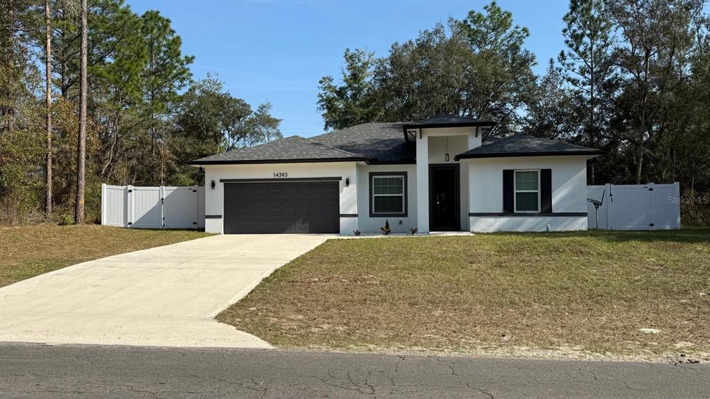 A single-story house with a white exterior, dark trim, and a two-car garage — 14393 SW 79TH TERRACE, OCALA, FL