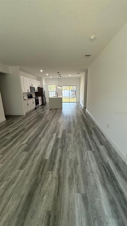 An open-concept kitchen and living area features white cabinetry, a center island, and wood-look flooring — 14393 SW 79TH TERRACE, OCALA, FL