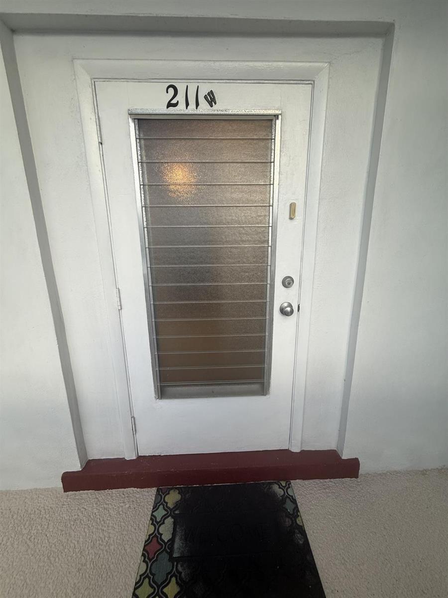 A white front door with a horizontal-slatted glass insert and the number 211 above it — 2050 NE 39th Street # 211w, Lighthouse Point FL 33064, LIGHTHOUSE POINT, FL