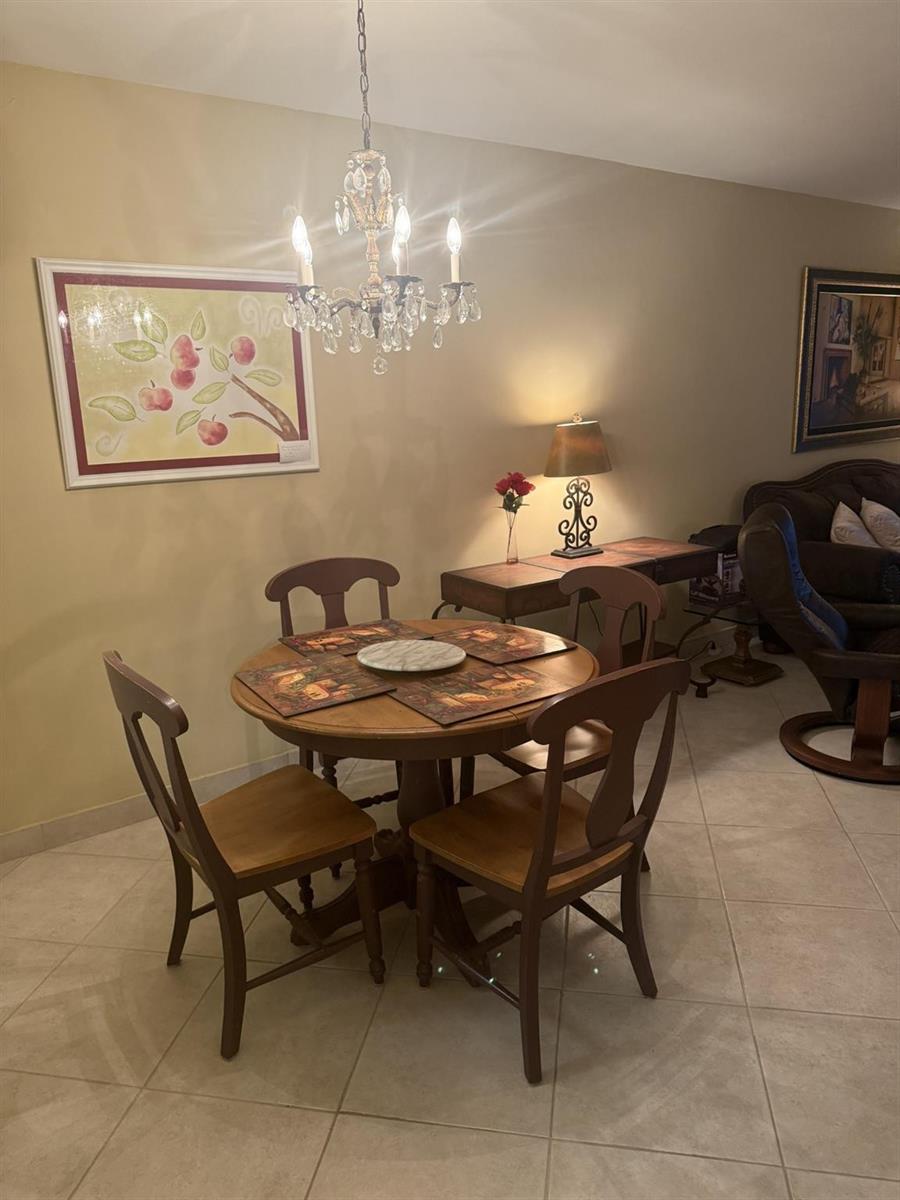 A dining area features a round wooden table, four chairs, and a crystal chandelier — 2050 NE 39th Street # 211w, Lighthouse Point FL 33064, LIGHTHOUSE POINT, FL