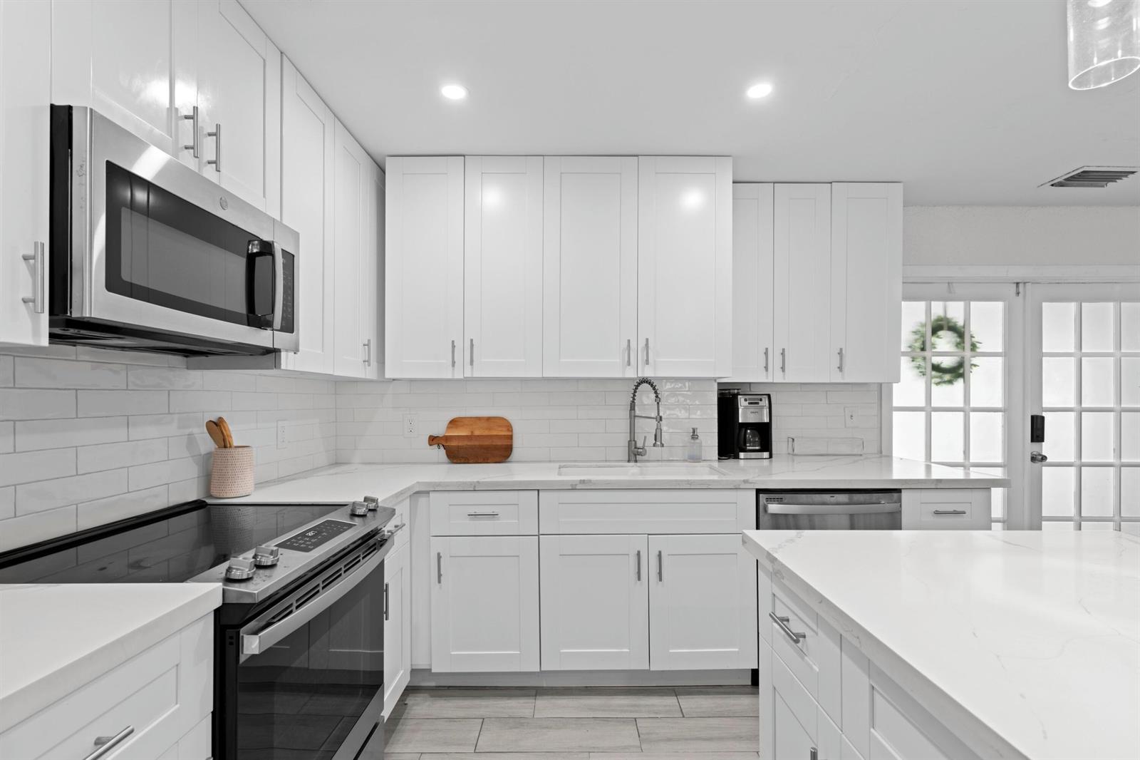 A modern kitchen features white shaker cabinets, stainless steel appliances, and white quartz countertops — 5285 Sunrise Boulevard, Delray Beach FL 33484, DELRAY BEACH, FL