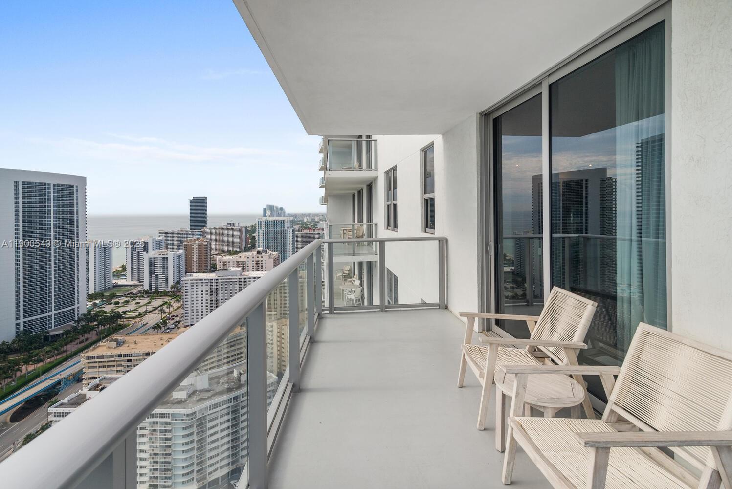 A high-rise balcony features two chairs, a small table, and a view of the city — 4010 S Ocean Dr # R2501, Hollywood FL 33019, HOLLYWOOD, FL