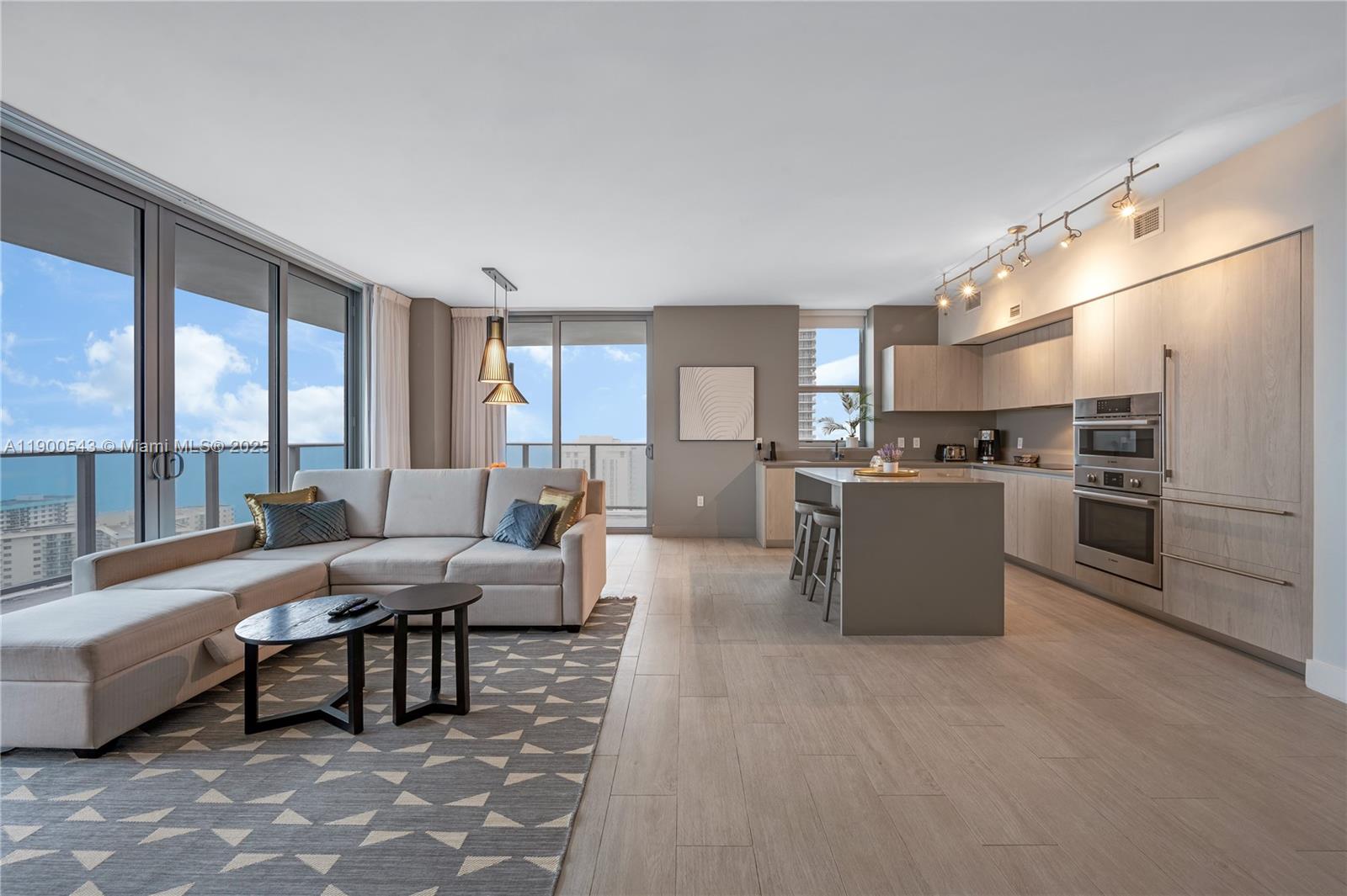 An open-concept living room and kitchen feature light wood cabinetry, a gray island, and balcony views — 4010 S Ocean Dr # R2501, Hollywood FL 33019, HOLLYWOOD, FL