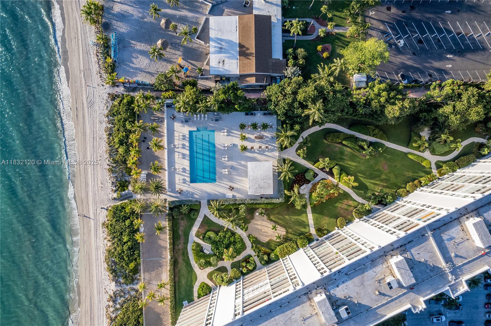 An aerial view shows a swimming pool, landscaped grounds, and a beach along the ocean — 615 Ocean Dr # 6A, Key Biscayne FL 33149, KEY BISCAYNE, FL