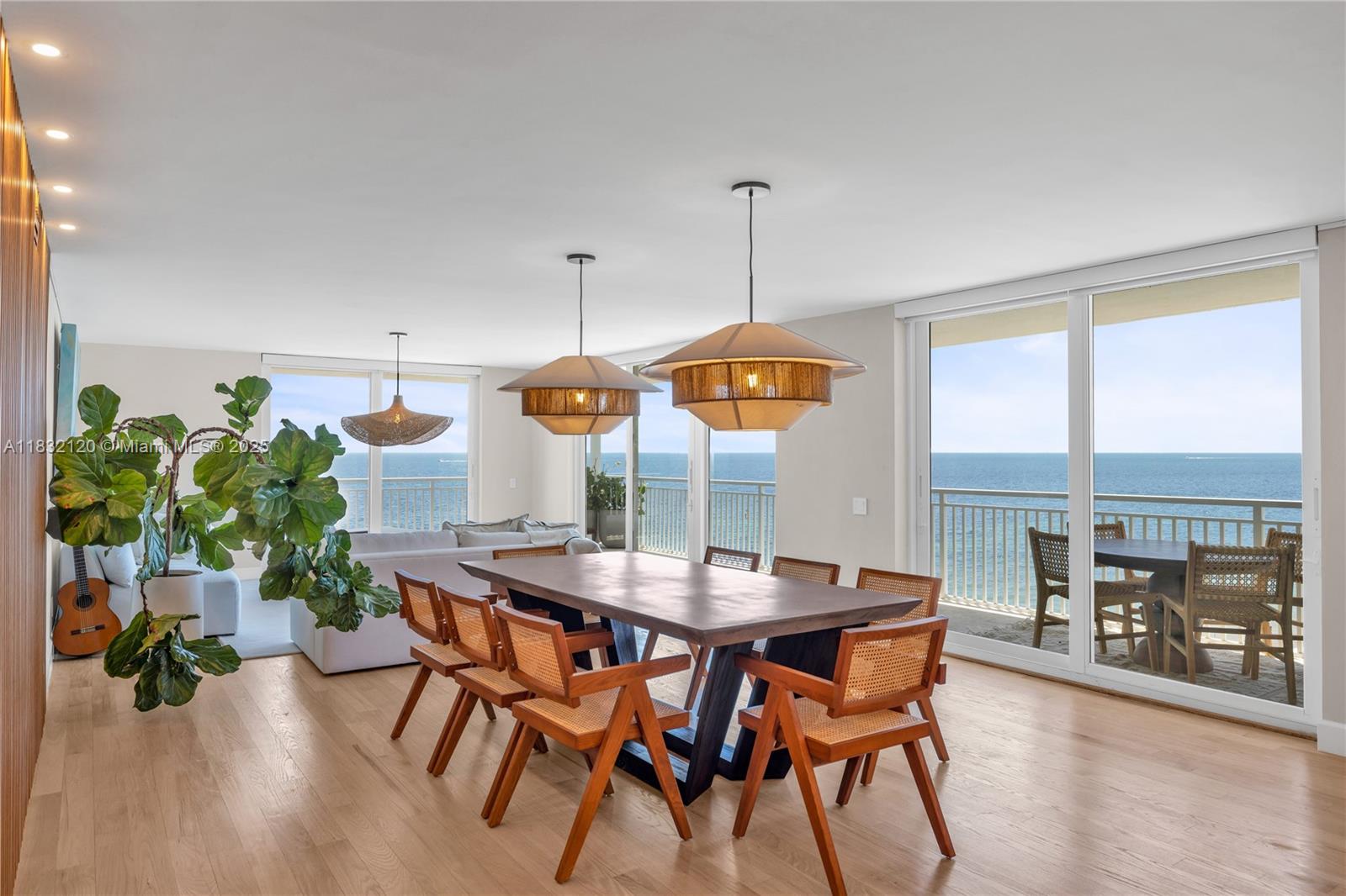 A dining area with a wooden table and cane chairs overlooks the ocean through sliding doors — 615 Ocean Dr # 6A, Key Biscayne FL 33149, KEY BISCAYNE, FL
