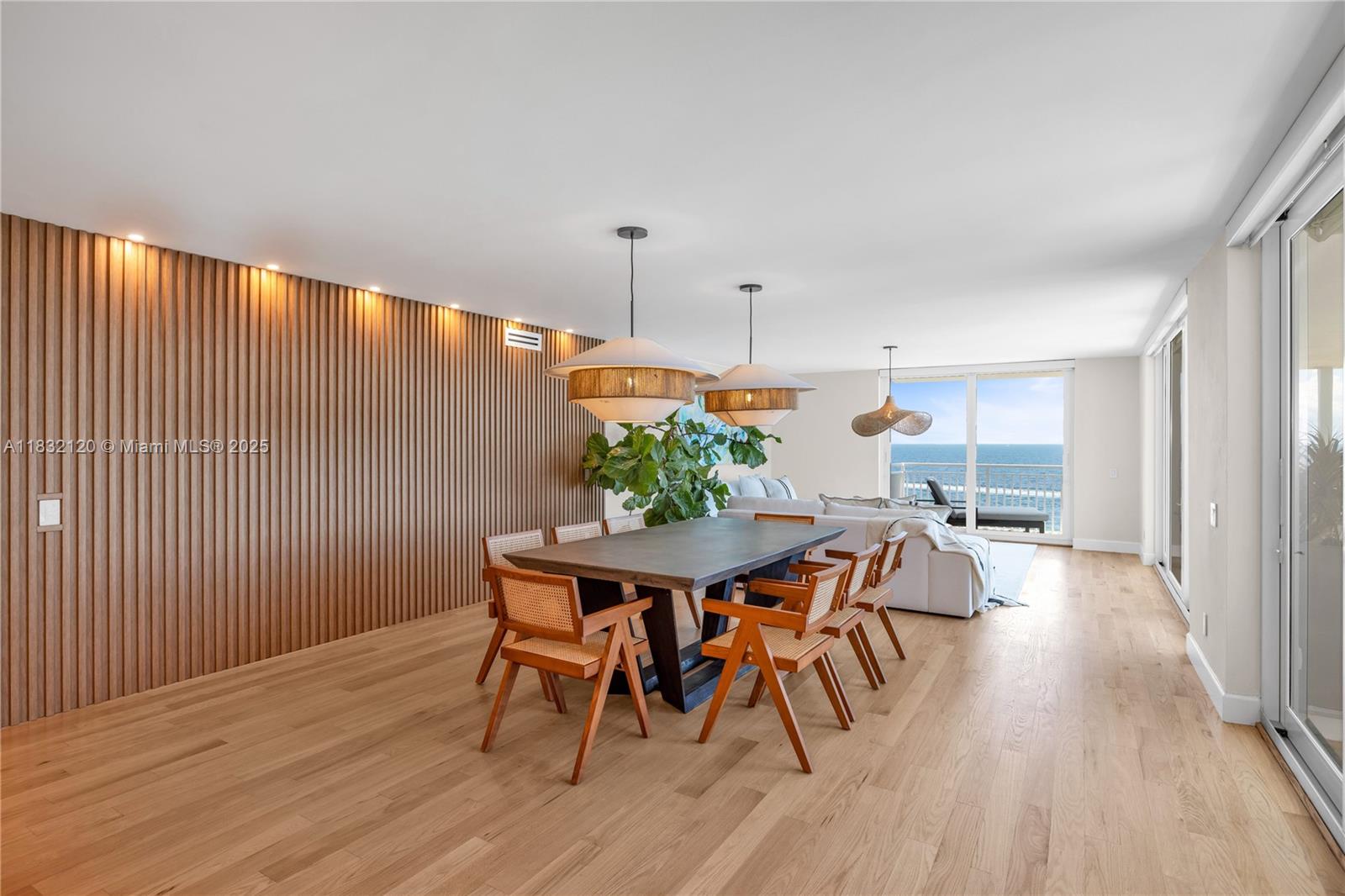 A dining area with a wood-slatted wall, pendant lights, and a view of the ocean — 615 Ocean Dr # 6A, Key Biscayne FL 33149, KEY BISCAYNE, FL
