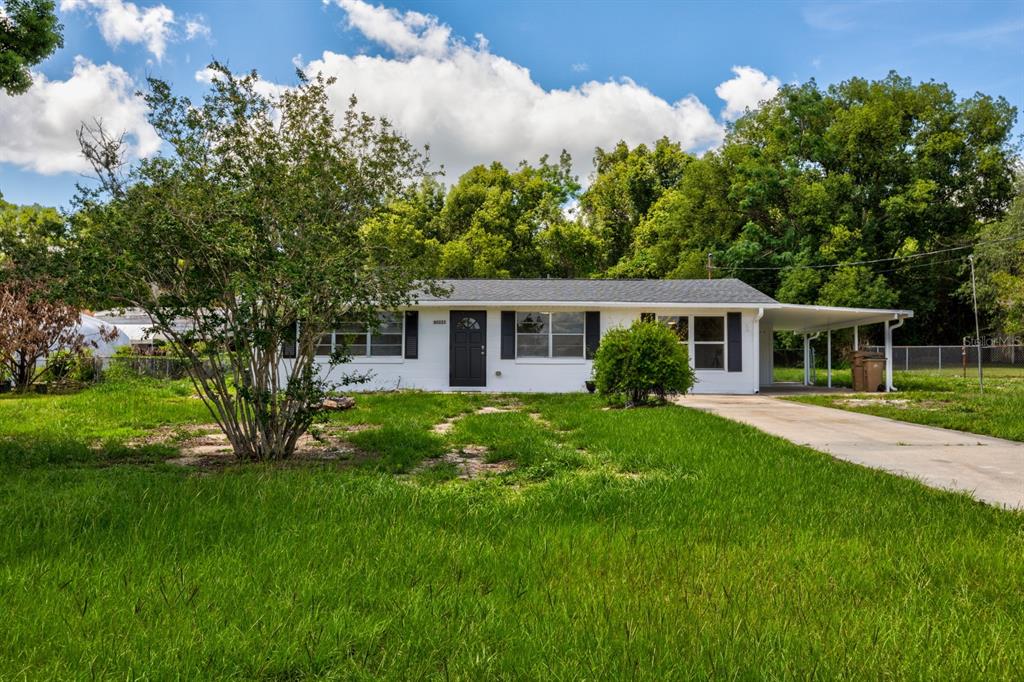 A white single-story house with a black front door and an attached carport — 5222 EAGLES NEST ROAD, FRUITLAND PARK, FL