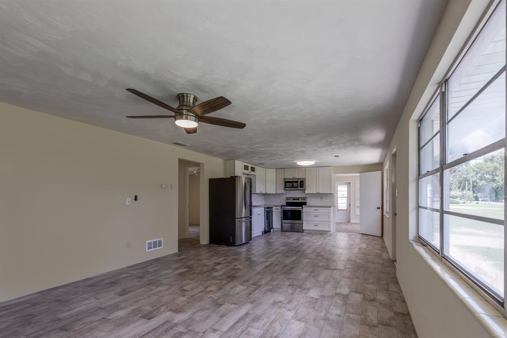 An open-concept kitchen and living area with wood-look tile flooring and white cabinetry — 5222 EAGLES NEST ROAD, FRUITLAND PARK, FL