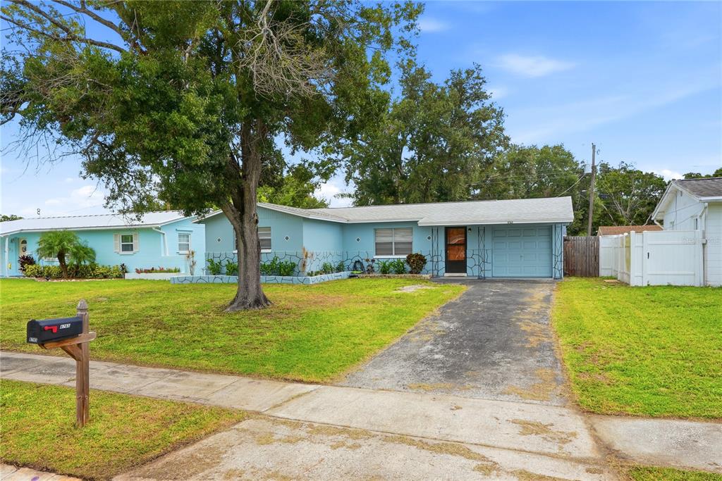 A light blue single-story house with a driveway, a large tree, and a front lawn — 8765 55TH WAY N, PINELLAS PARK, FL