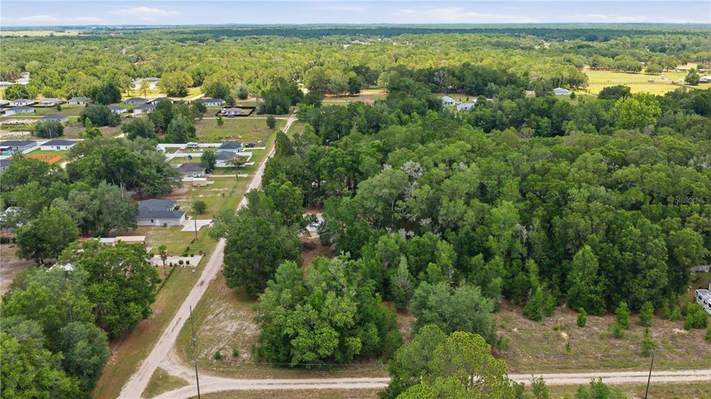 An aerial view shows a rural residential area with houses, dirt roads, and dense trees — SW 131ST TERRACE, DUNNELLON, FL
