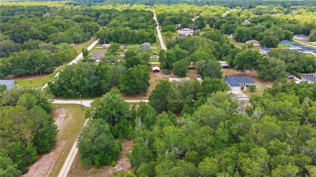 An aerial view shows a rural residential area with scattered houses, dirt roads, and dense trees — SW 131ST TERRACE, DUNNELLON, FL