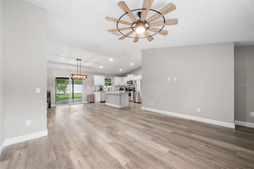 An open-concept living area features light wood-look flooring, gray walls, and a kitchen with white cabinetry — 6771 CHERRY ROAD, OCALA, FL