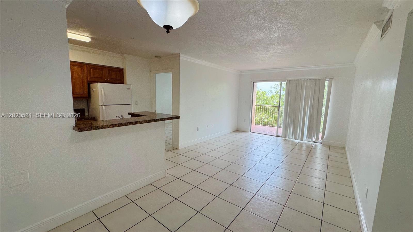 An open-concept living area features light gray walls, white tile flooring, and a kitchen counter — 15221 SW 80th St # 406, Miami FL 33193, MIAMI, FL