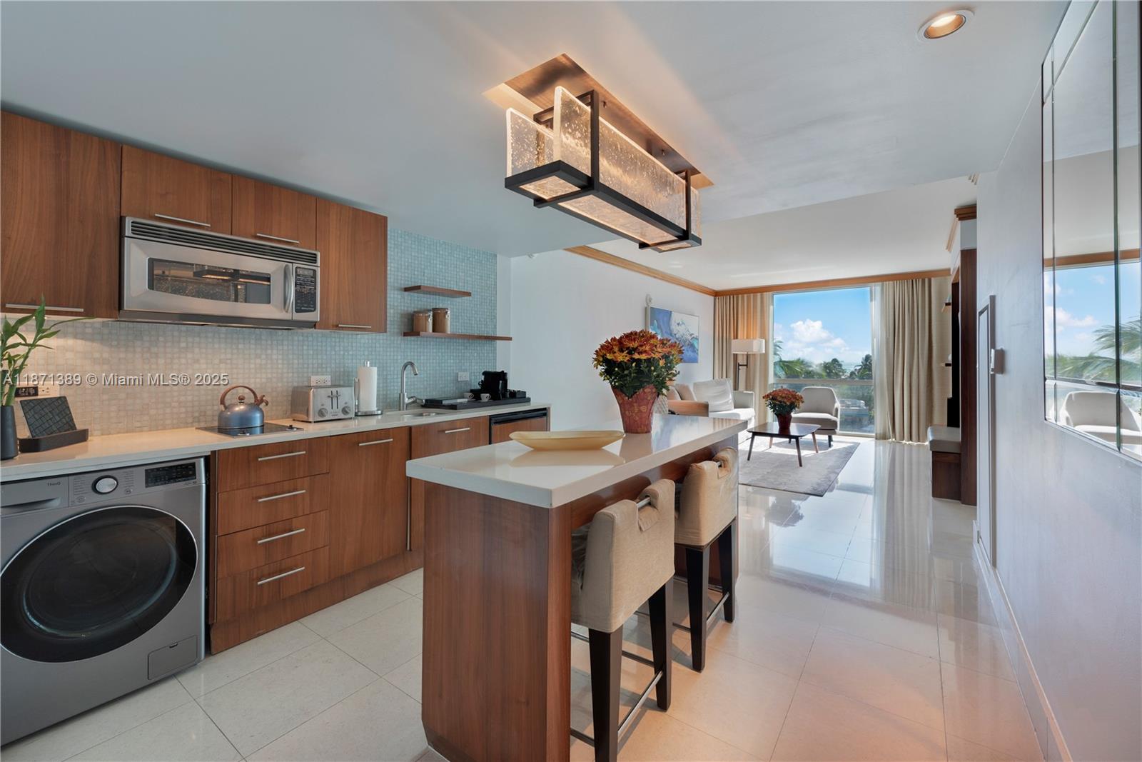 A modern kitchen with wood cabinetry, a breakfast bar, and an adjacent living area — 6801 Collins Ave, Miami Beach FL 33141, MIAMI BEACH, FL