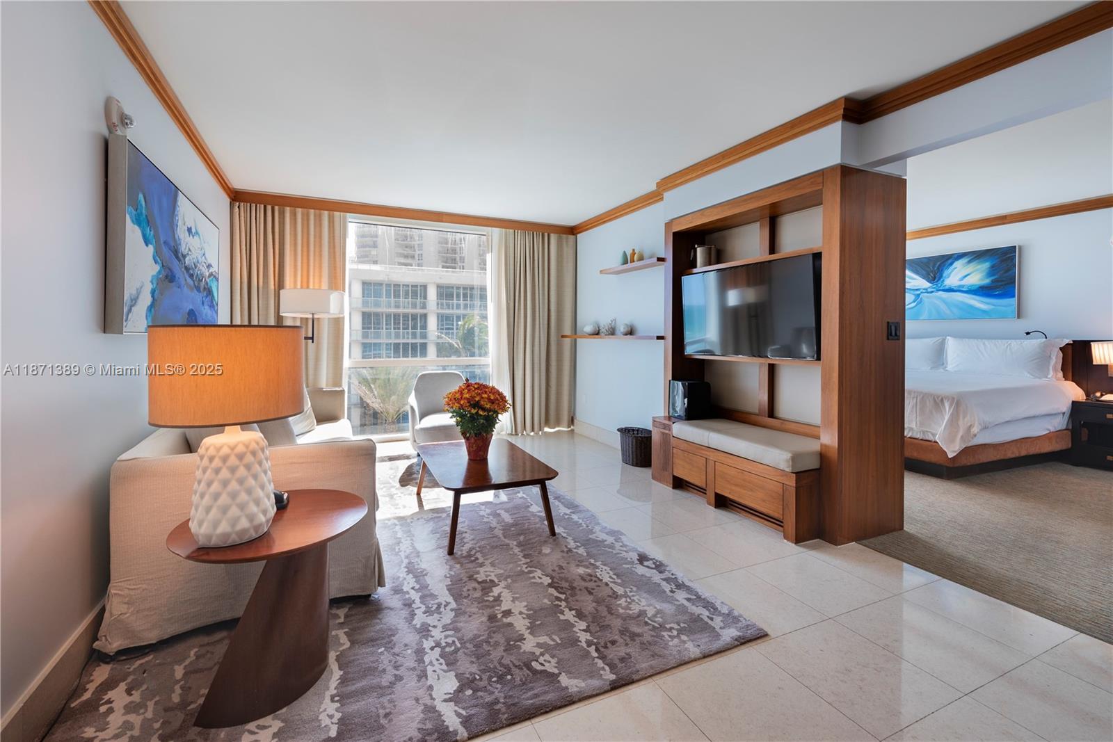A living area with a sofa, coffee table, and television unit opens into a bedroom — 6801 Collins Ave, Miami Beach FL 33141, MIAMI BEACH, FL
