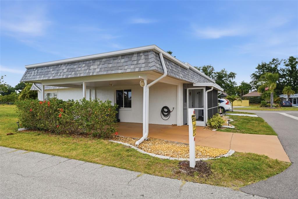 A single-story home with a covered carport, a screened entryway, and a landscaped front yard — 690 CIRCLEWOOD DRIVE UNIT W8, VENICE, FL