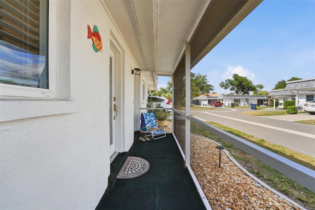 A screened-in porch with a green carpet floor overlooks a paved street and neighborhood homes — 690 CIRCLEWOOD DRIVE UNIT W8, VENICE, FL
