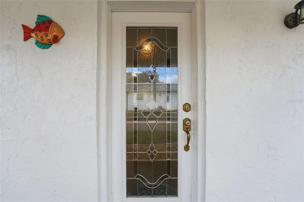 A white front door with a decorative glass insert and a fish wall ornament — 690 CIRCLEWOOD DRIVE UNIT W8, VENICE, FL