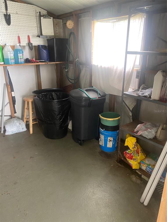 A storage shed with a pegboard wall, shelving, trash cans, and a window — 38210 WILLIAMS AIRE STREET, DADE CITY, FL