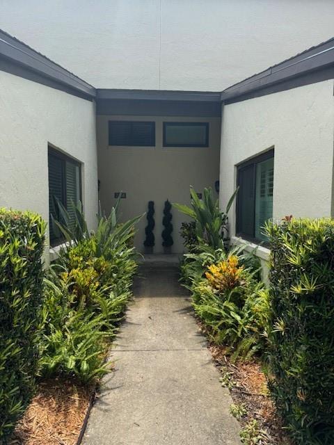 A concrete walkway leads to the entrance of a residential building flanked by green bushes — 1637 SE PARADISE CIRCLE UNIT 205, CRYSTAL RIVER, FL