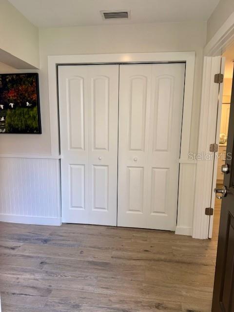 A room features white bi-fold closet doors, wood-look flooring, and white wainscoting on the wall — 1637 SE PARADISE CIRCLE UNIT 205, CRYSTAL RIVER, FL