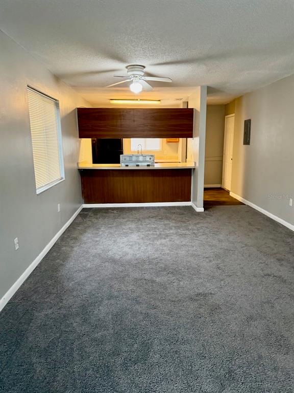A carpeted living room features a breakfast bar opening to a kitchen with wood cabinetry — 105 CORY LANE, WINTER SPRINGS, FL