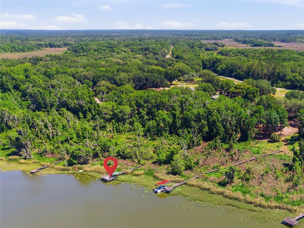 An aerial view shows a lakefront property with two wooden docks extending into the water — 3980 SE 183RD AVENUE ROAD, OCKLAWAHA, FL