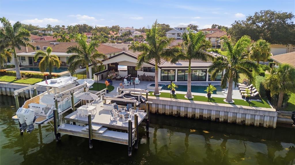 An aerial view shows a waterfront house with a pool, boat dock, and palm trees — 2022 HAWAII AVENUE NE, ST PETERSBURG, FL