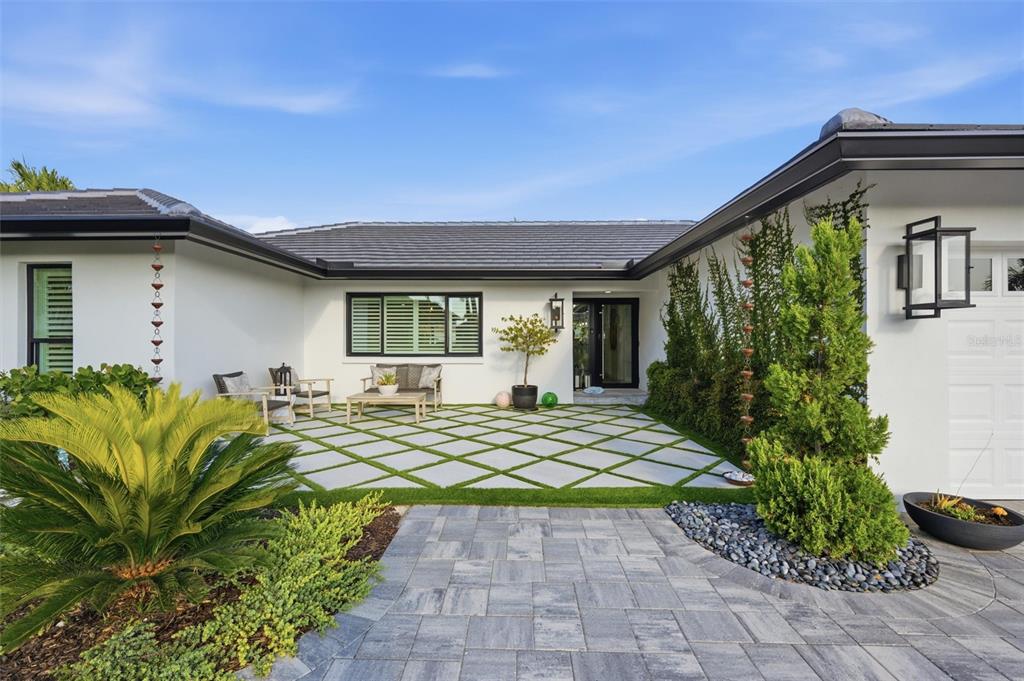 A modern home exterior features a white facade, a diamond-patterned patio, and a paved walkway — 2022 HAWAII AVENUE NE, ST PETERSBURG, FL