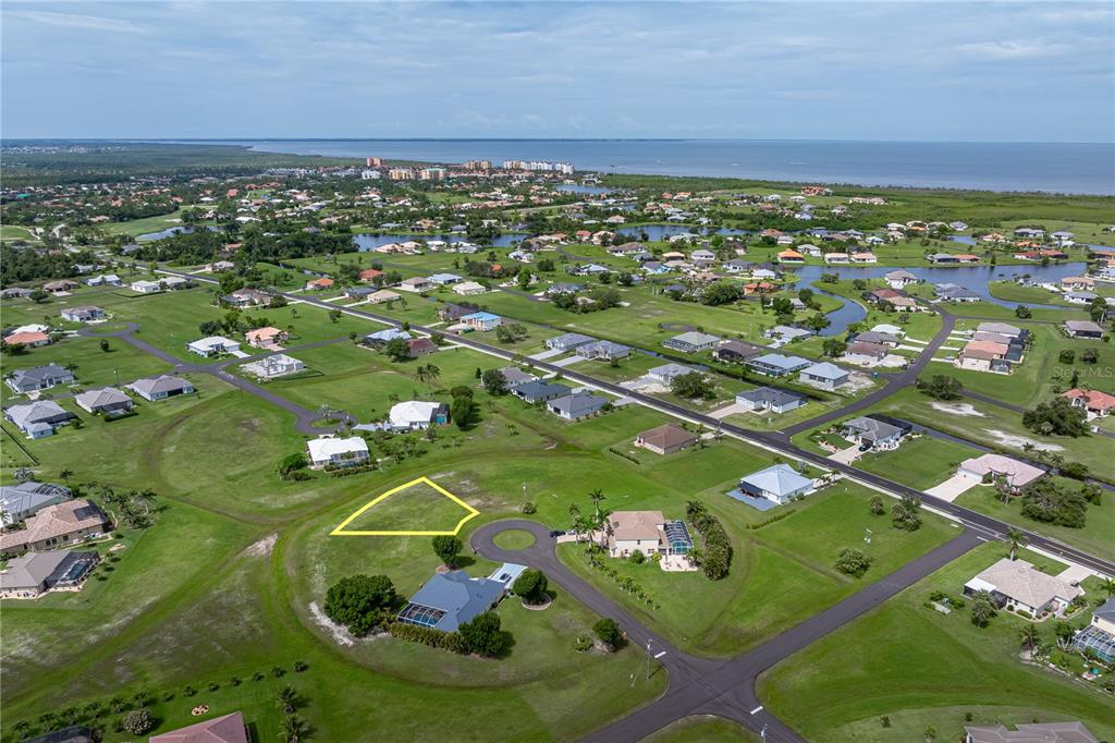 An aerial view shows a vacant residential lot outlined in yellow within a suburban neighborhood — 17318 NAIAD COURT, PUNTA GORDA, FL