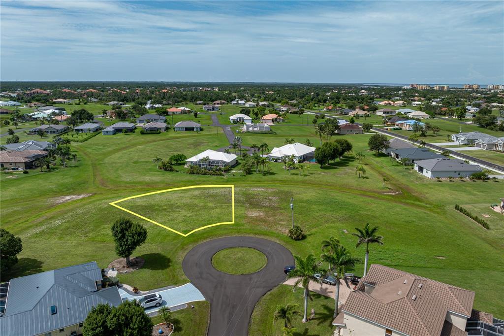 An aerial view shows a vacant, yellow-outlined residential lot situated at the end of a cul-de-sac — 17318 NAIAD COURT, PUNTA GORDA, FL