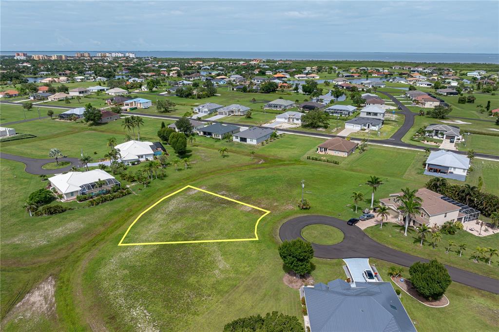 An aerial view shows a vacant, yellow-outlined residential lot situated in a suburban neighborhood — 17318 NAIAD COURT, PUNTA GORDA, FL