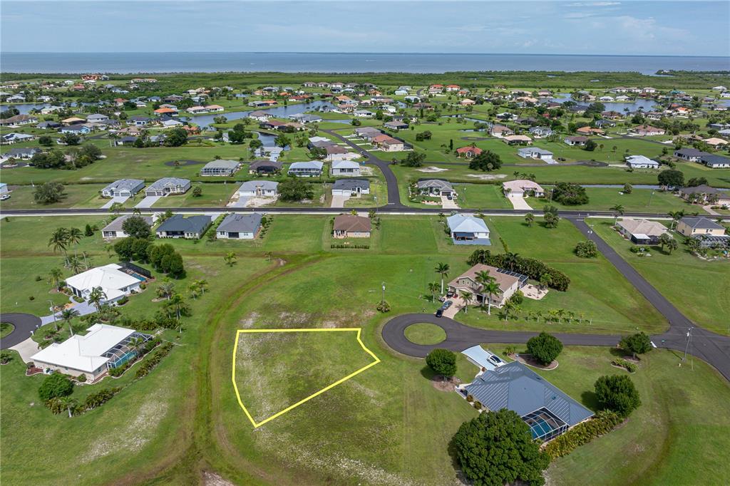 An aerial view shows a vacant residential lot outlined in yellow within a suburban neighborhood — 17318 NAIAD COURT, PUNTA GORDA, FL