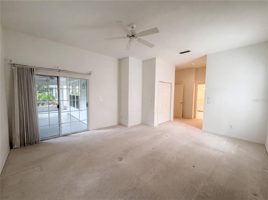 A carpeted room features a ceiling fan, sliding glass doors, and a doorway to a hallway — 3319 NEWBLISS CIRCLE, ORMOND BEACH, FL