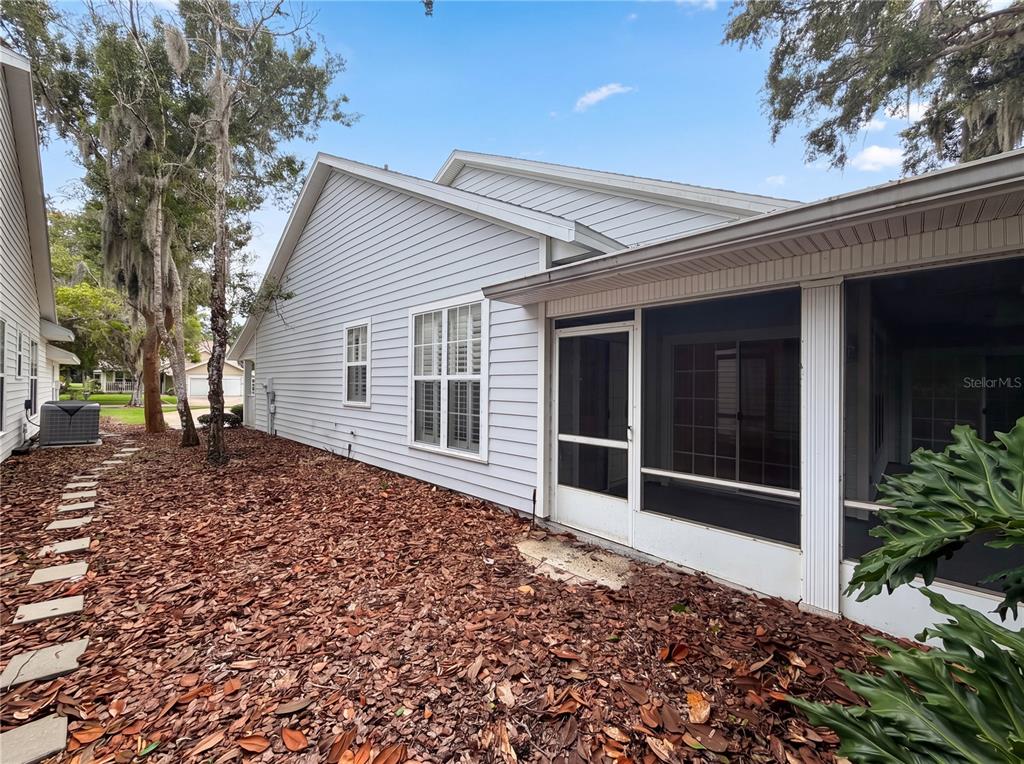 The exterior of a house features light-colored siding, a screened-in porch, and a leaf-covered yard — 3319 NEWBLISS CIRCLE, ORMOND BEACH, FL