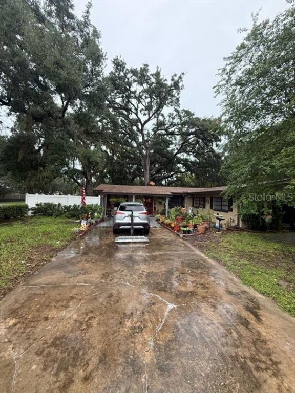 A single-story house with a concrete driveway, a carport, and large trees in the yard — 5423 ASHMEADE ROAD, ORLANDO, FL
