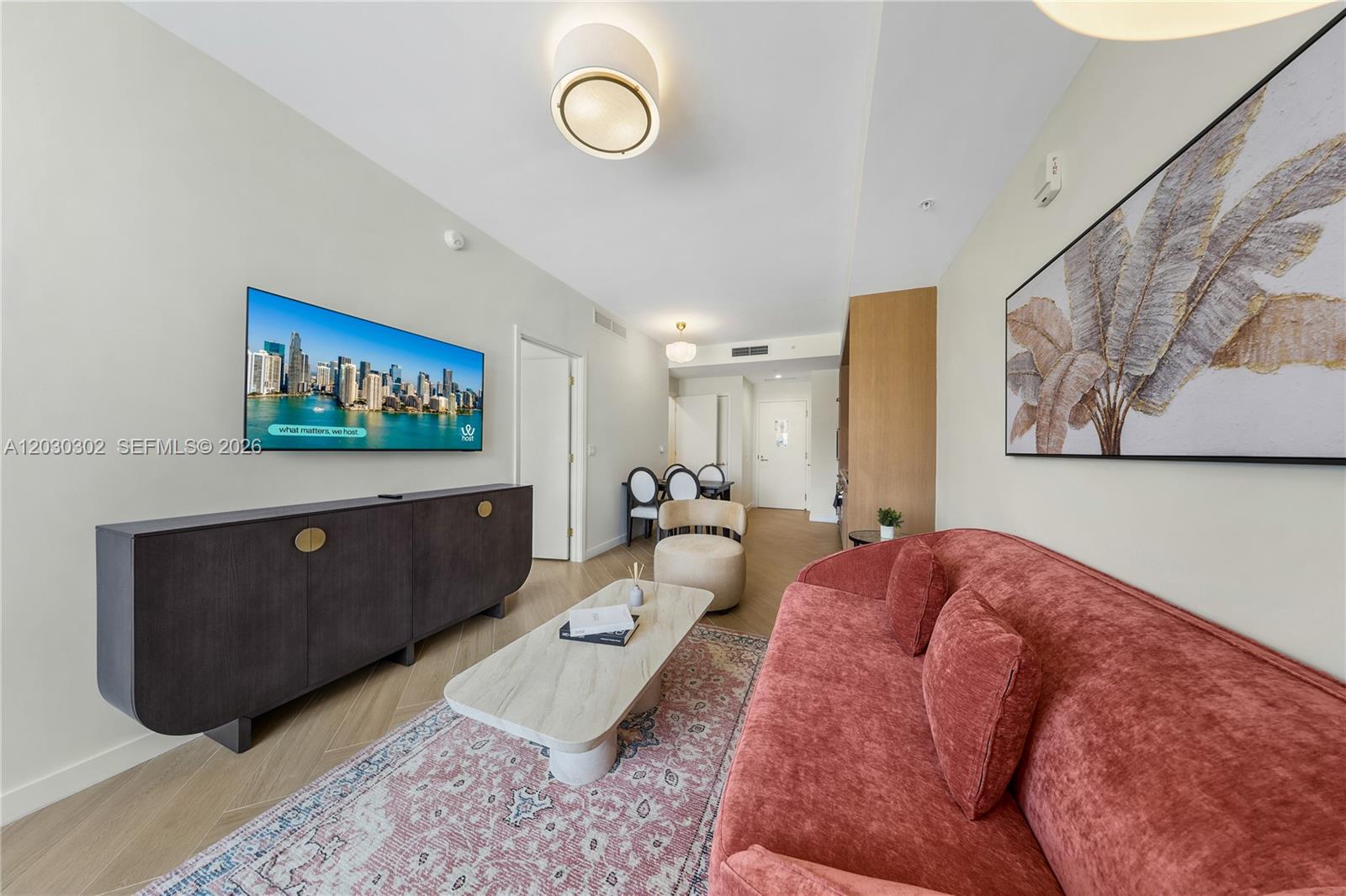 A living room features a red sofa, a coffee table, and a wall-mounted television — 2700 NW 2nd Ave # 218, Miami FL 33127, MIAMI, FL