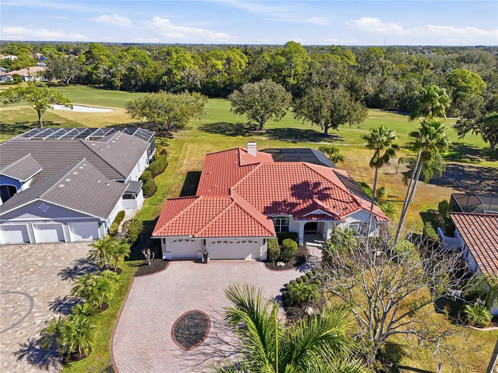 A single-story house with a red tile roof and a paved driveway with a planter — 7321 LINKS COURT, SARASOTA, FL