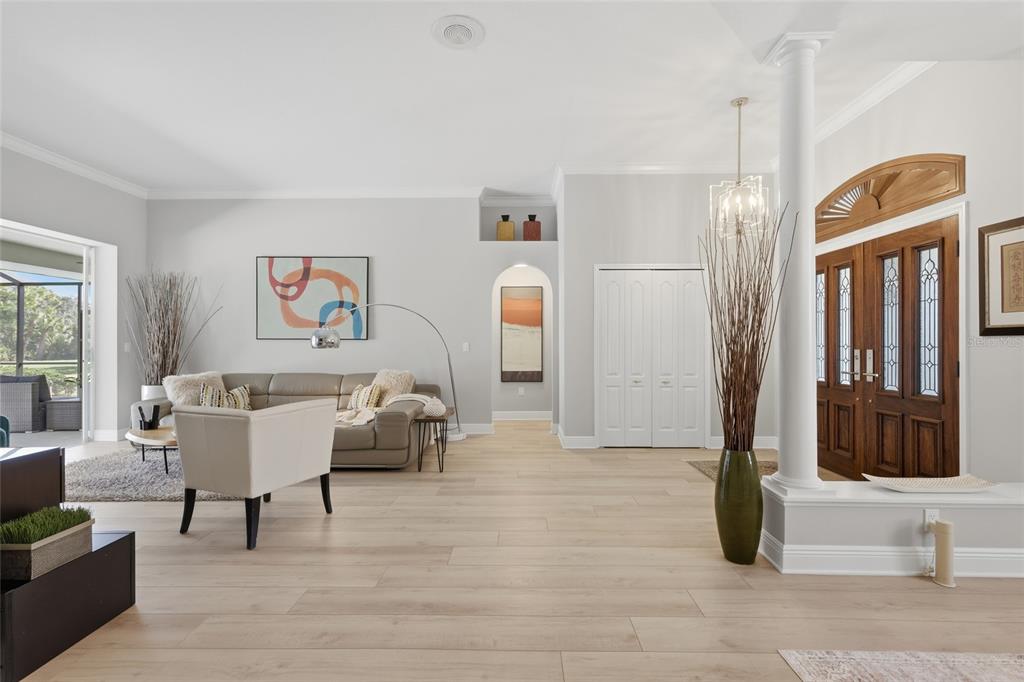 A living room with a sectional sofa, white armchair, television, and sliding doors to a pool — 7321 LINKS COURT, SARASOTA, FL
