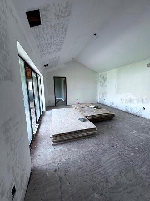 An unfinished room features exposed plywood flooring, bare drywall, and a large sliding glass door — 16540 WISTERIA DRIVE, FORT MYERS, FL