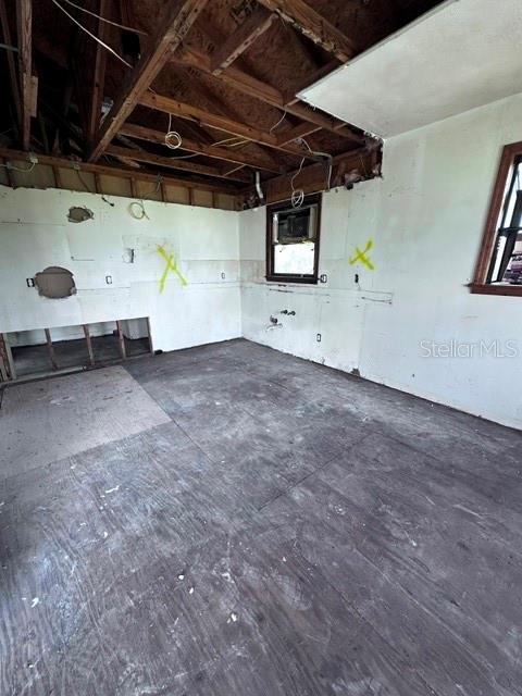 An unfinished room with exposed ceiling rafters, plywood subflooring, and marked walls — 16540 WISTERIA DRIVE, FORT MYERS, FL
