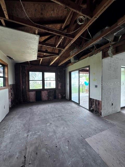 An interior room under construction features exposed ceiling rafters, bare plywood flooring, and sliding doors — 16540 WISTERIA DRIVE, FORT MYERS, FL