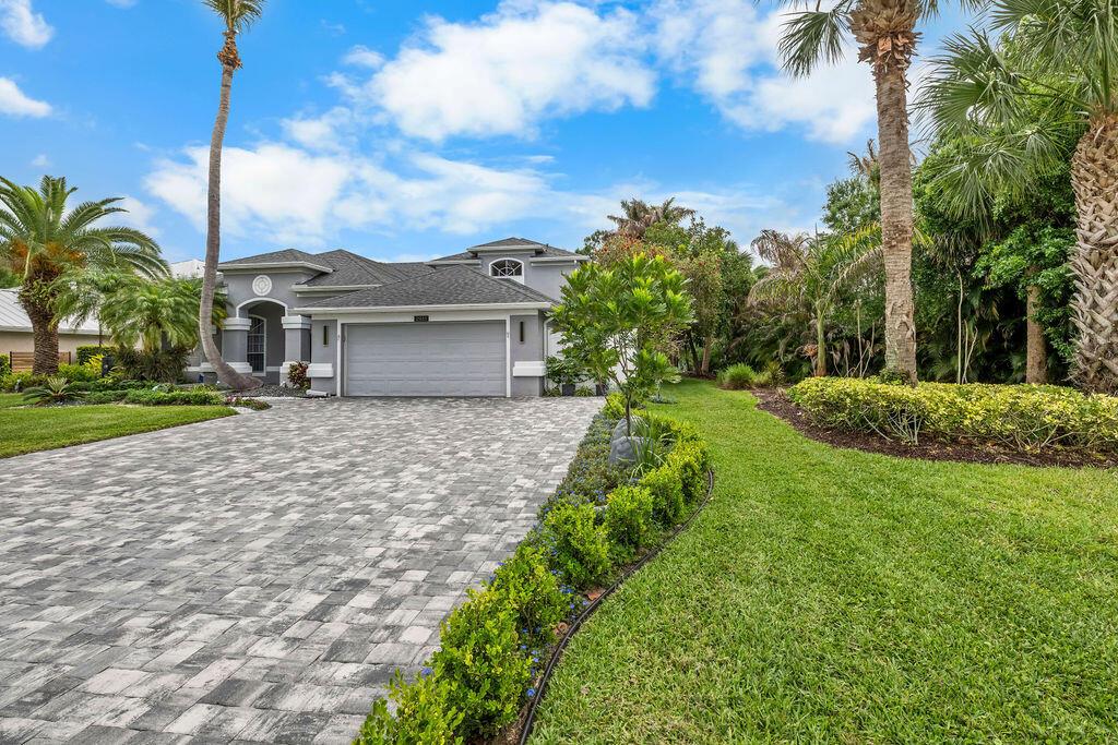 A gray single-story house with a paved driveway, palm trees, and manicured landscaping — 2981 NW Windemere Drive, Jensen Beach FL 34957, JENSEN BEACH, FL