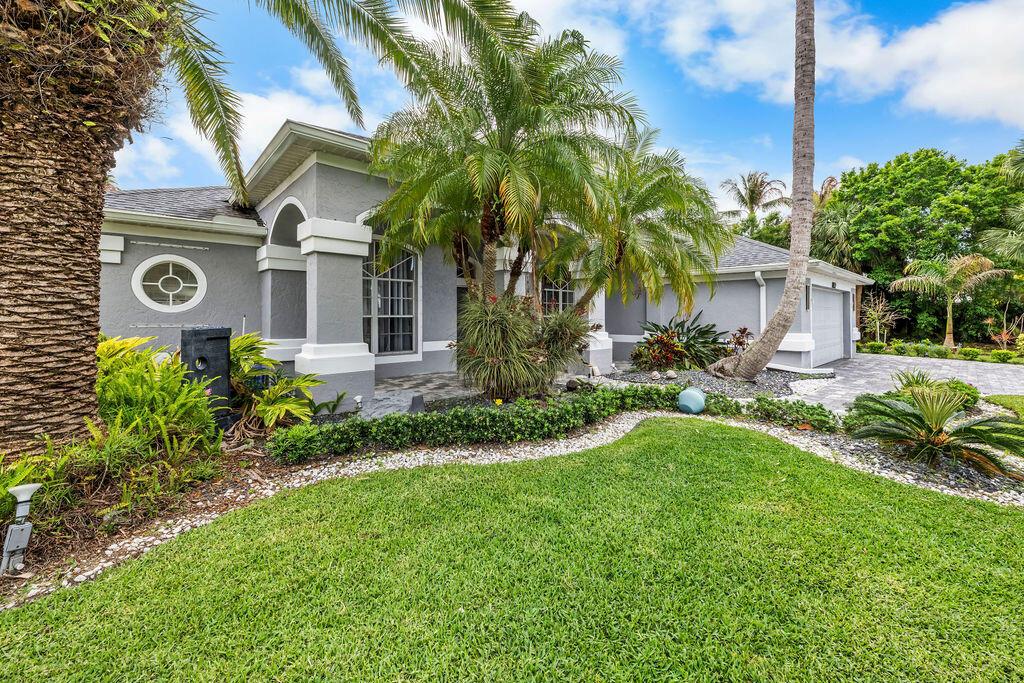 A gray single-story house with a palm tree, manicured landscaping, and a paved driveway — 2981 NW Windemere Drive, Jensen Beach FL 34957, JENSEN BEACH, FL