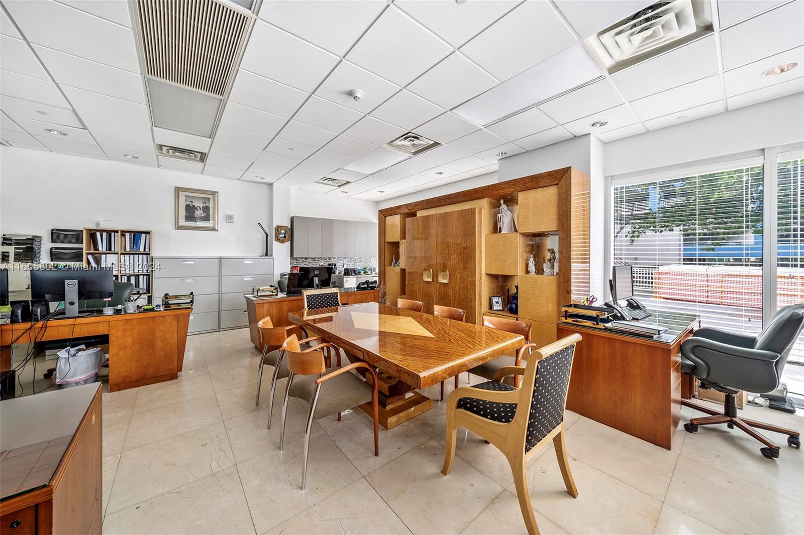 An office space features a central wooden conference table, multiple desks, and large windows — 2101 Brickell Ave, Miami FL 33129, MIAMI, FL